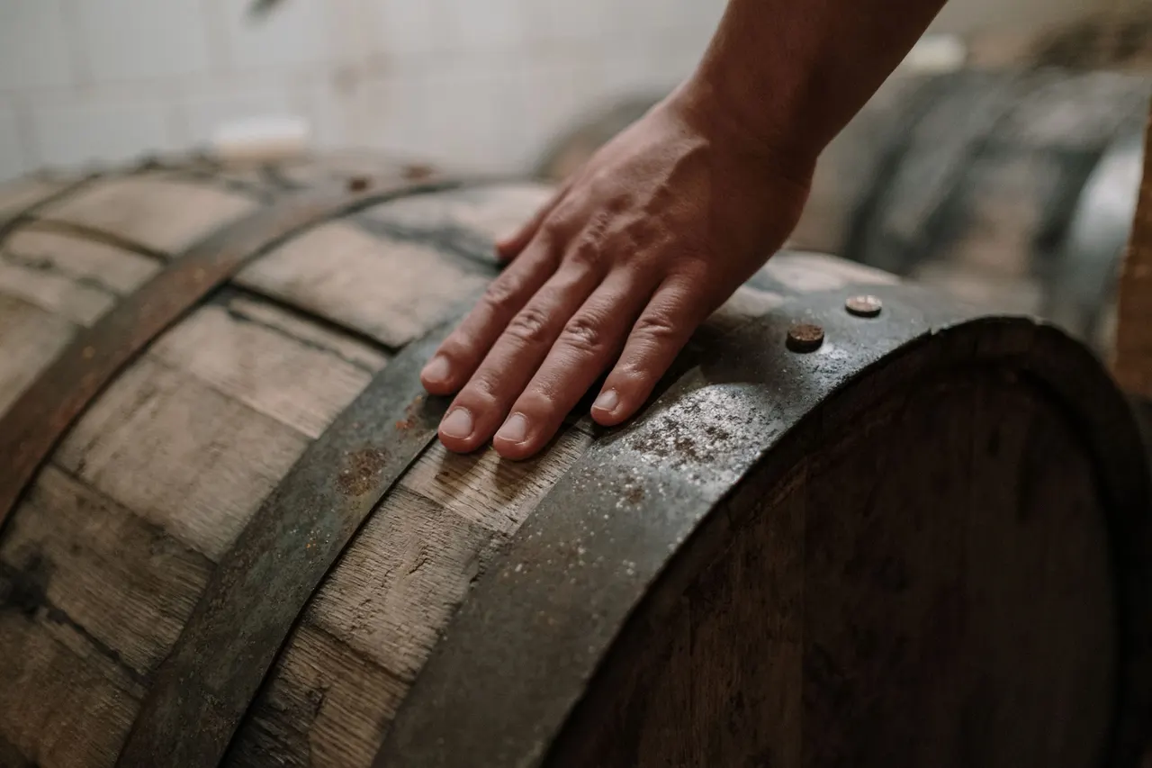 A hand resting on a charred oak barrel