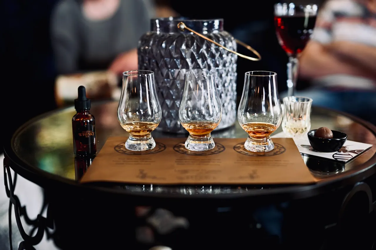 Three tasting glasses of amber whiskey on a round bar table